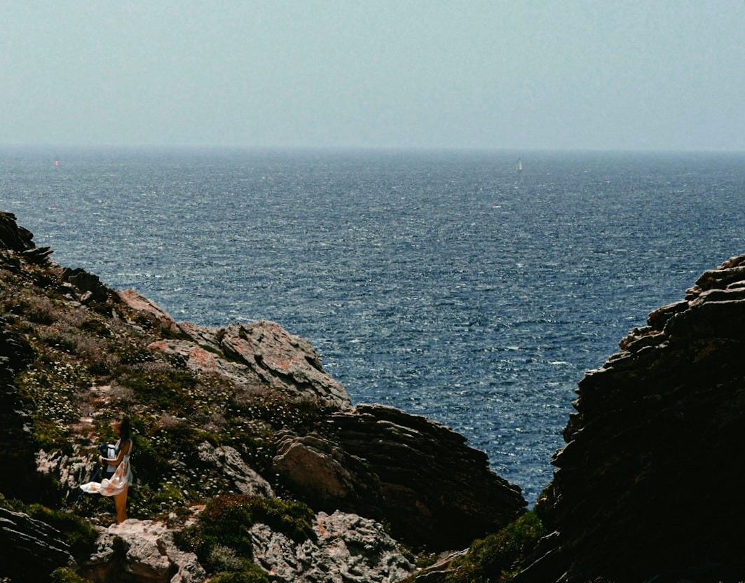 A man standing on top of a cliff next to the ocean