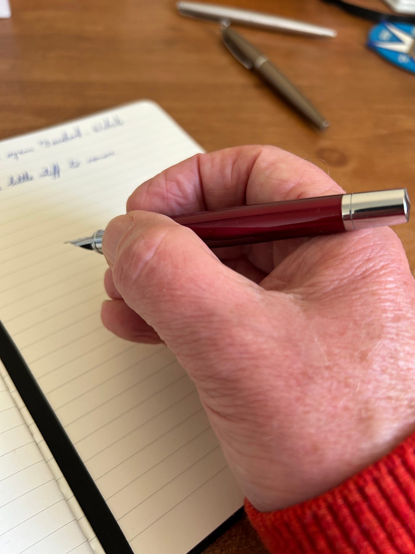 An Ellington Classic Fountain pen in the hand of a man hovering over a notebook laid on a desk. Photo: Roland MIllward