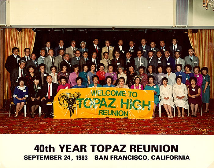 A large group of former students gathered for the 40th Topaz High reunion, holding a colorful banner, in San Francisco, 1983.