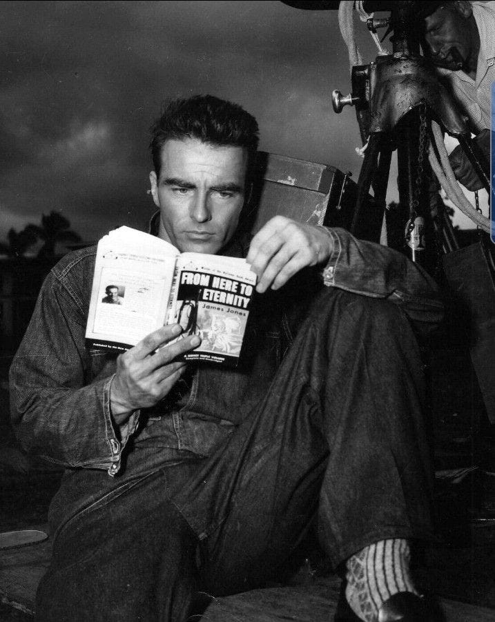 This may contain: a man sitting on the ground reading a book