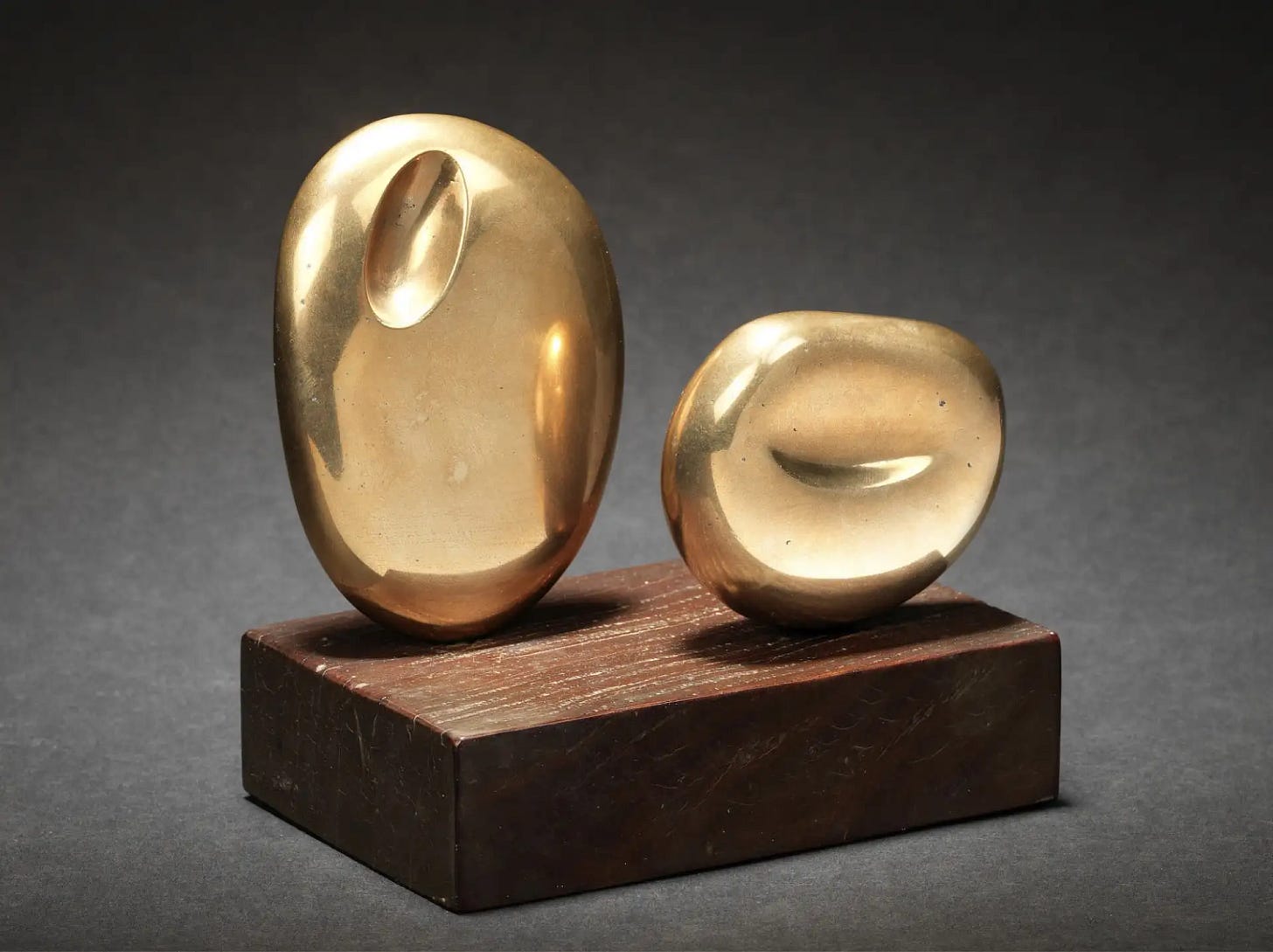 Barbara Hepworth’s polished bronze sculpture “Two Forms (Atlantic)” from 1961, composed of two smooth organic shapes mounted on a wooden base.