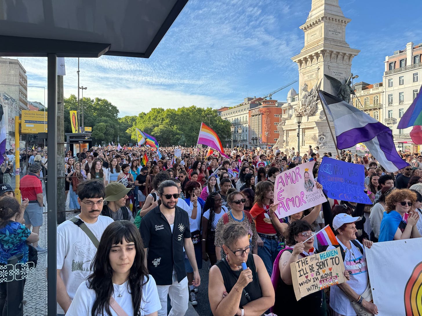 A crowd with different colored flags marches through a historic plaza. A crowd with different colored flags marches through a historic plaza.