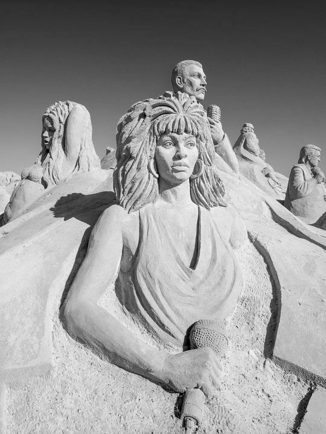 a sand sculpture of a woman sitting in the sand