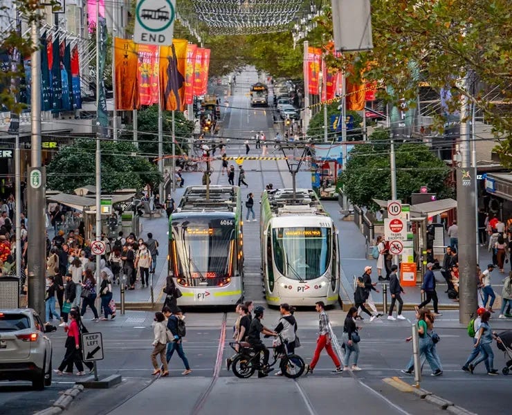 Trams and pedestrians on a busy city street.
