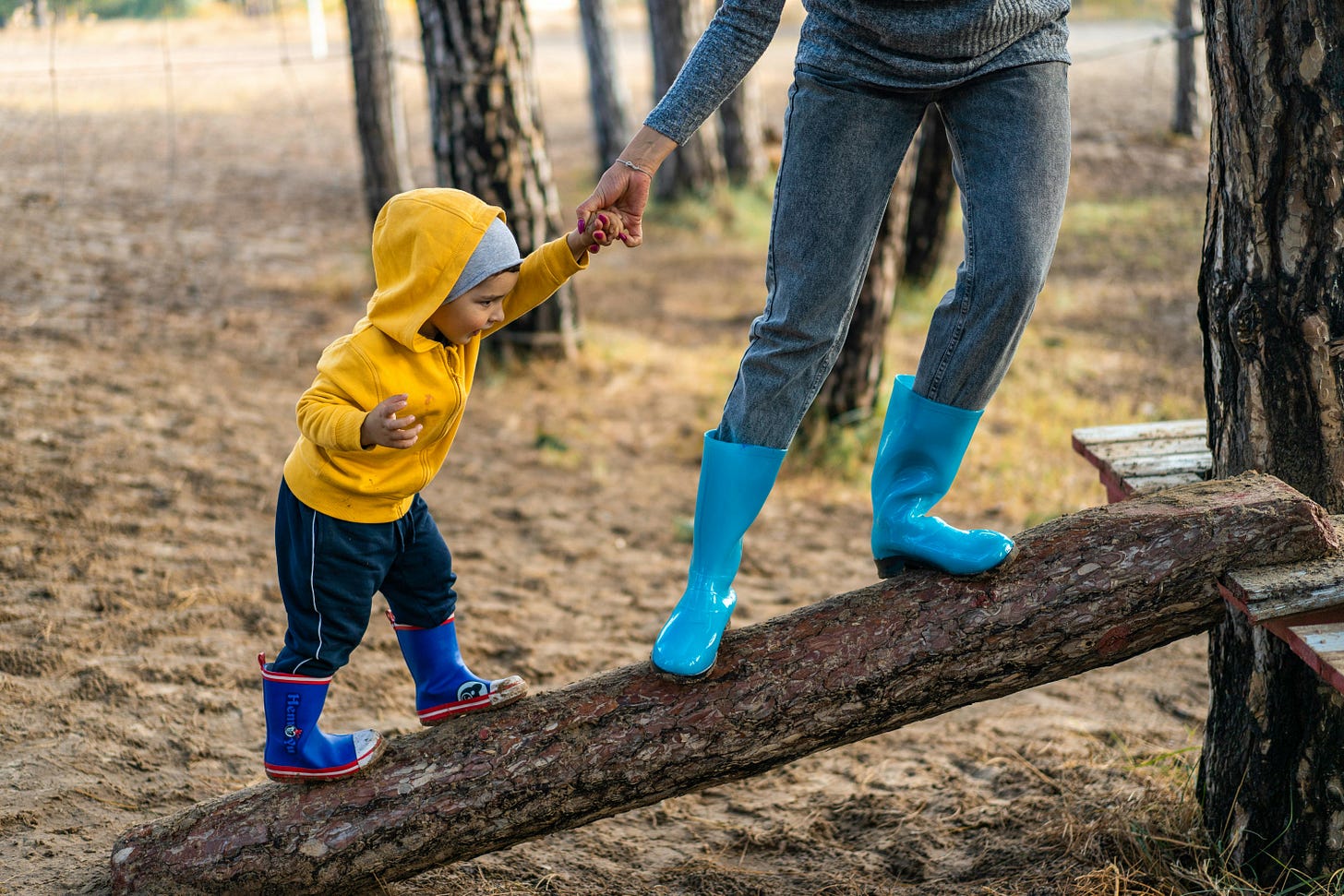 An auntie holding her nephew's hand as they climb a tree branch