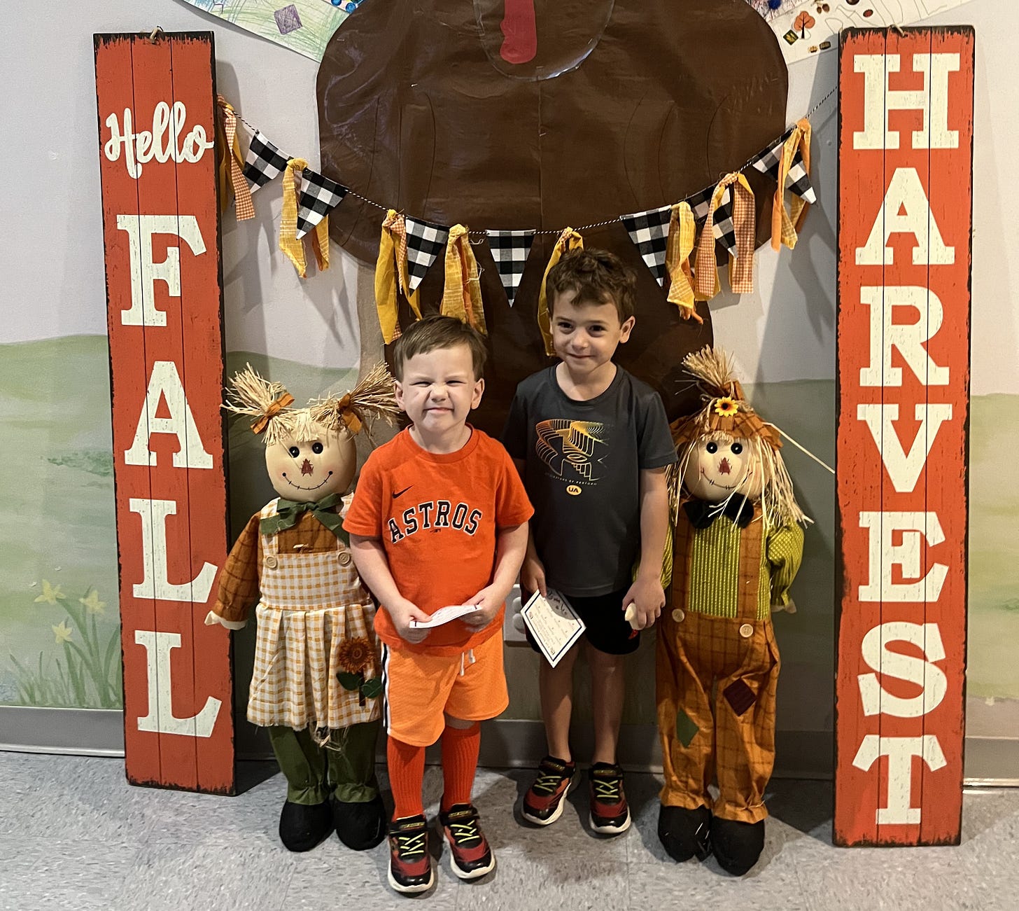 two boys standing in front of a fall harvest sign two boys standing in front of a fall harvest sign
