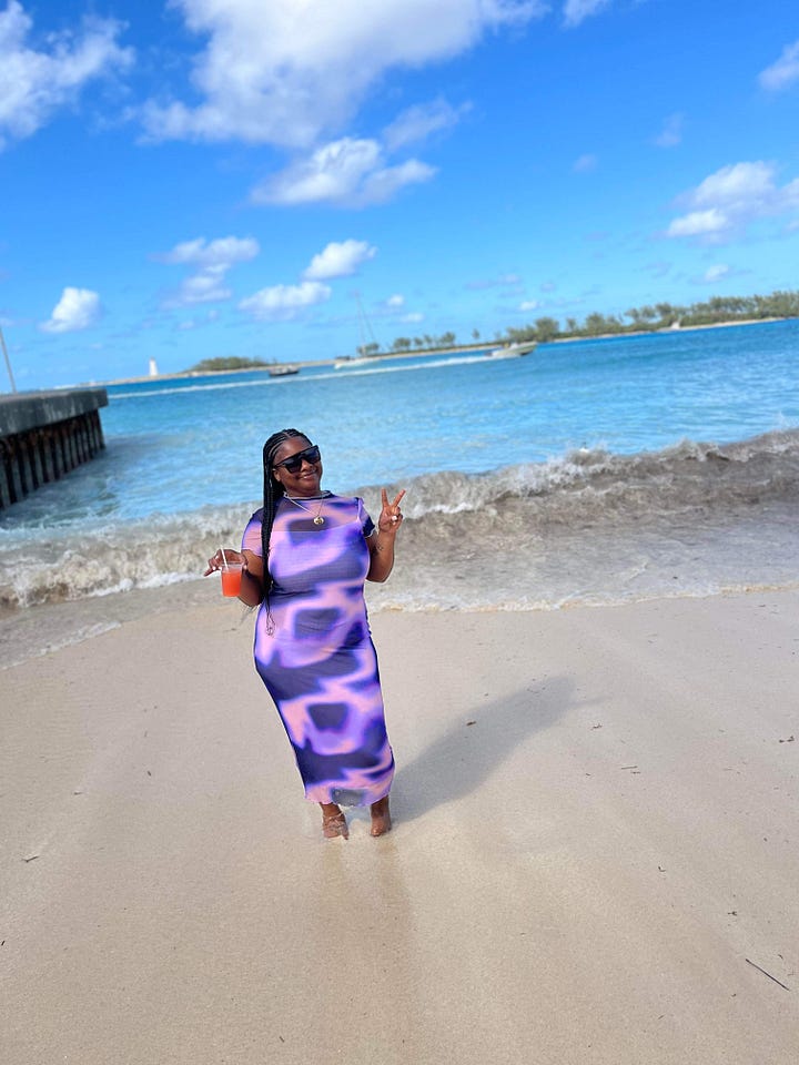 Left to right: Black woman sits a swim up bar with a yellow drink in her hand smiling. Black woman dressed in a purple and blue dress with a drink in her hand in front of crystal blue water. Black woman smiles in front of a beach in a white t-shirt and abstract matching short set. Black Woman stands in front of a blue and white sign that reads Oasis Lagoon, wearing a brown and white swim suit.