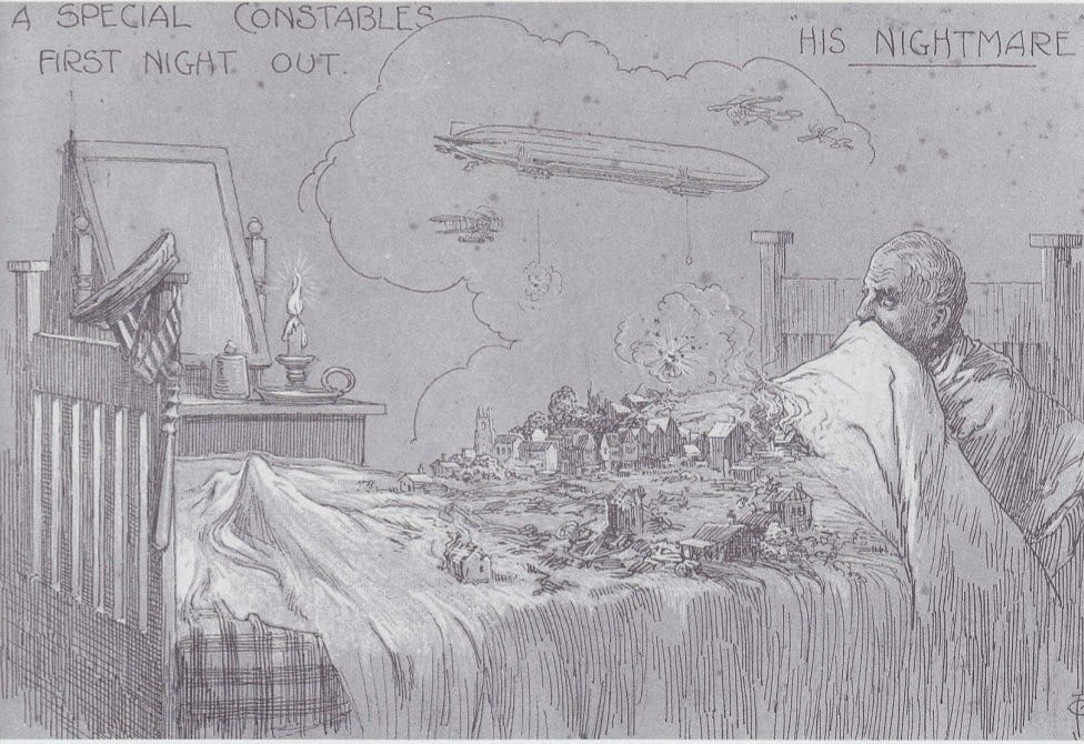 A man sits upright in bed with the covers pulled up to his nose. In front of him, on the blanket, a zeppelin bombs a small village. Several buildings are destroyed and/or on fire. On the bottom left bedpost his special constable hat, armband and truncheon hang. His candle is left burning on the nightstand as he is too afraid to be in darkness.