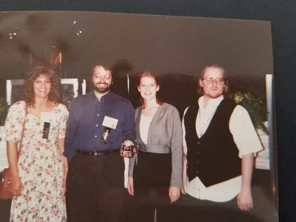 A group photograph from the 1994 Diamond Comic Distribution trade show: Casey Brebberman (Marketing), Ron Richardson (Sales), Carol Monahan, and Aaron Anderson (Customer Service) A group photograph from the 1994 Diamond Comic Distribution trade show: Casey Brebberman (Marketing), Ron Richardson (Sales), Carol Monahan, and Aaron Anderson (Customer Service)