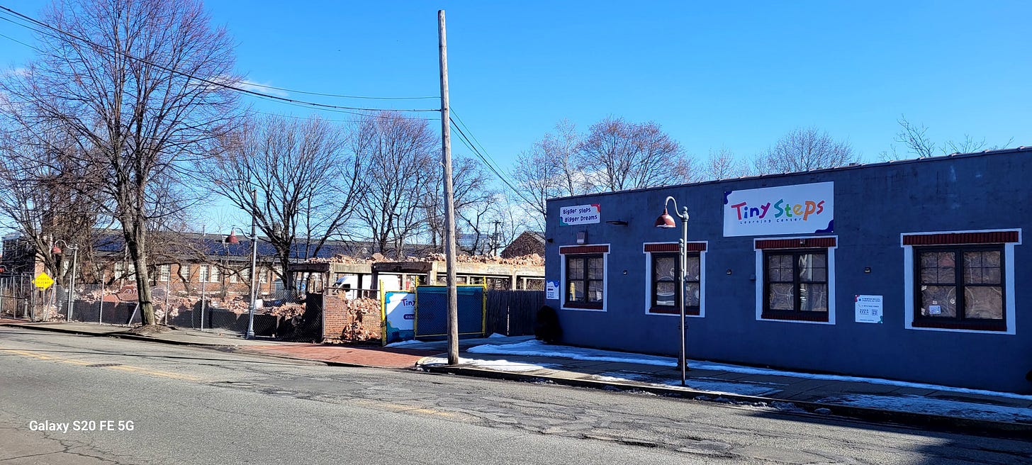 On the right, a preschool called "Tiny Steps Learning Center", with the tagline "Bigger Steps, Bigger Dreams". On the left, a large pile of bricks from a recently demolished building.