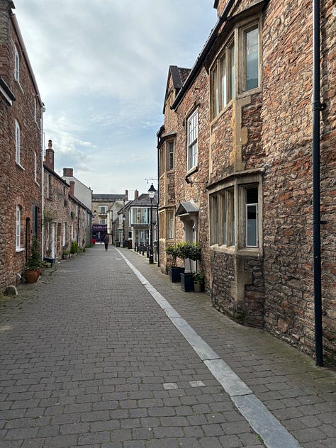 Three views of attractions in Wells, England. A cathedral, a town crier, an English street.
