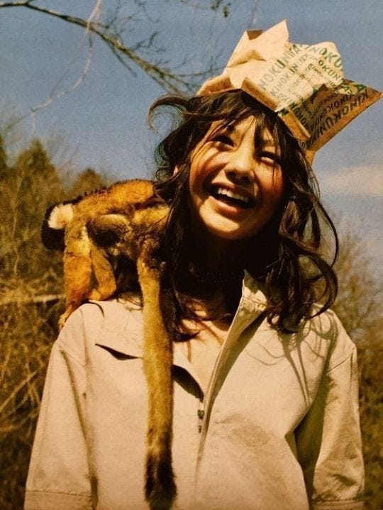 This may contain: a woman holding a cat on her shoulders and wearing a hat with money sticking out of it