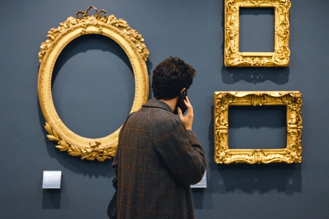 man in black jacket standing in front of brown wooden frames
