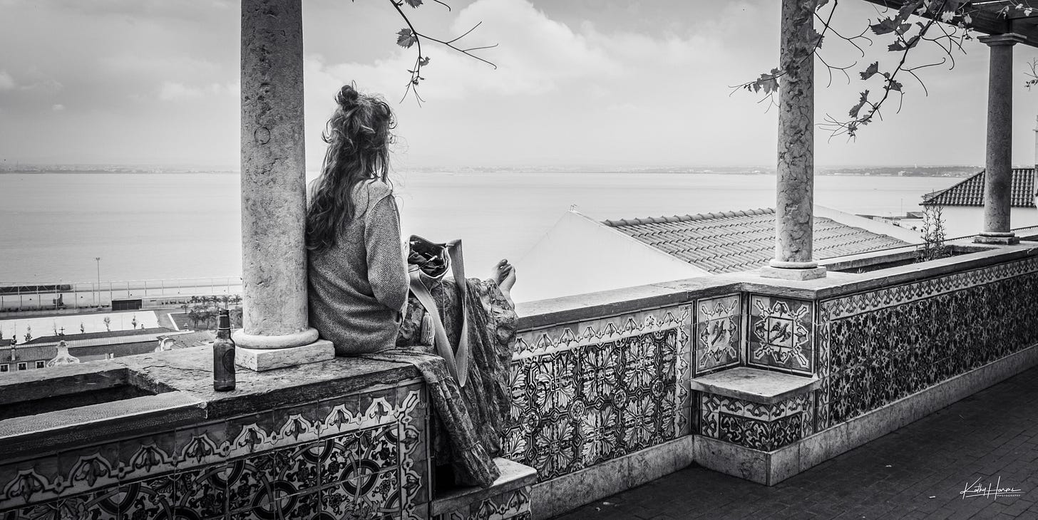 A woman sitting on a wall looking towards a river
