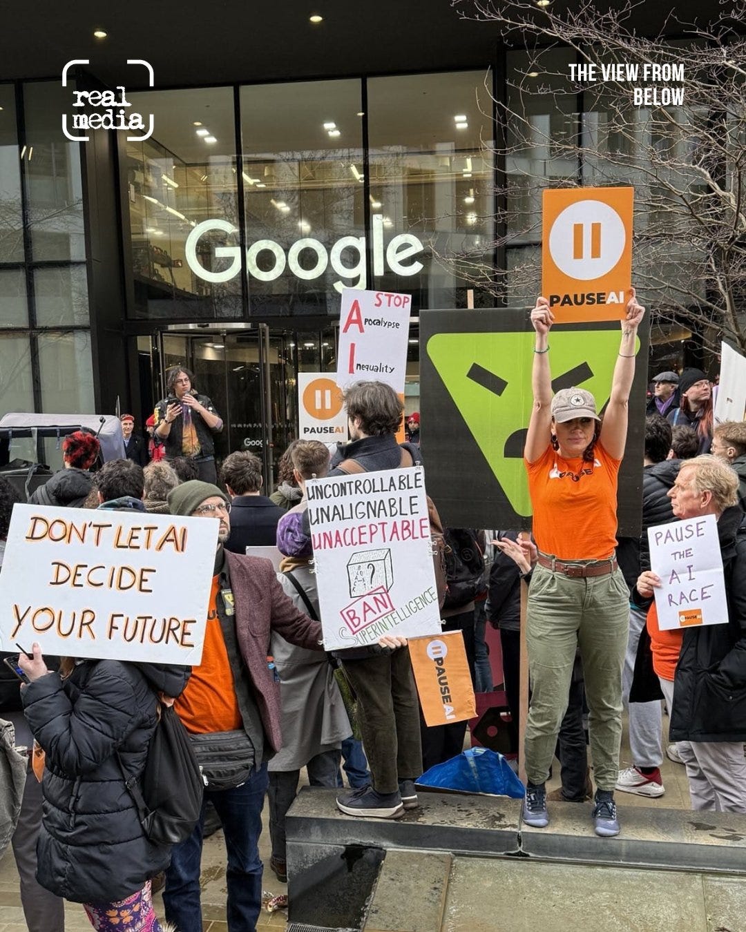 A crowd protests outside a Google office holding signs about artificial intelligence. Placards read “Pause AI,” “Don’t let AI decide your future,” “Pause the AI race,” and “Uncontrollable, unalignable, unacceptable,” while one protester holds a large Pause AI sign above their head.