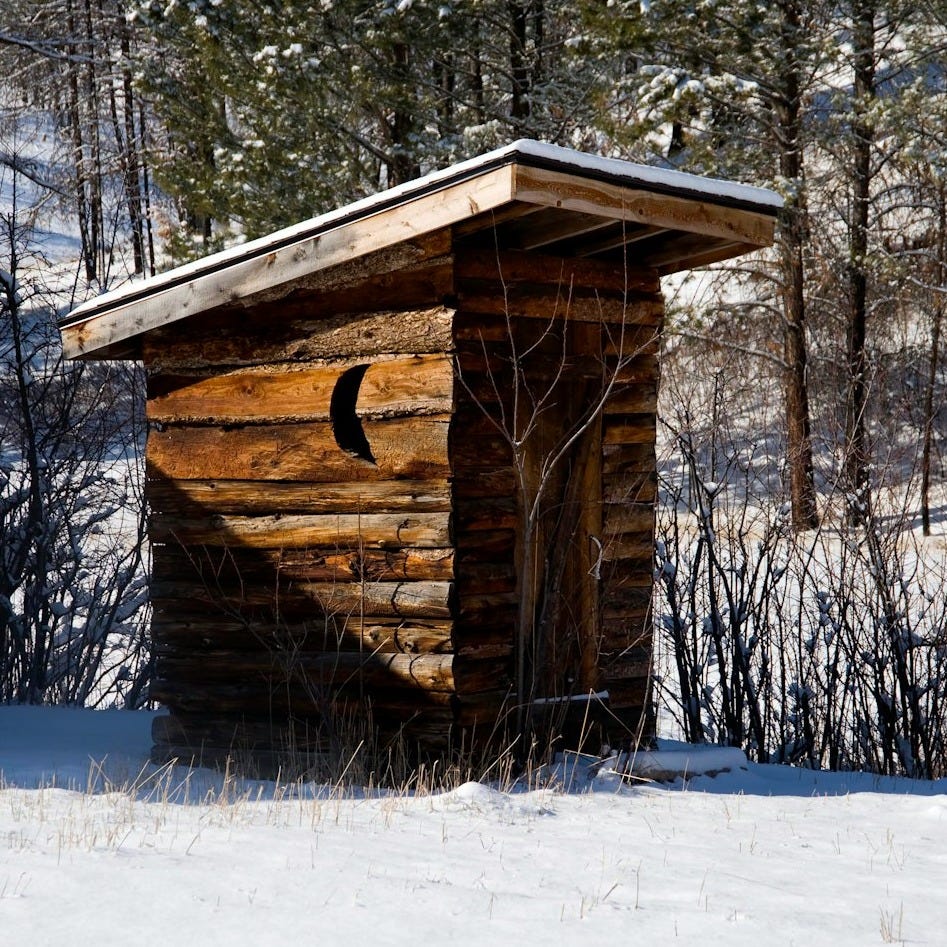 a small log cabin in the middle of a snowy field a small log cabin in the middle of a snowy field
