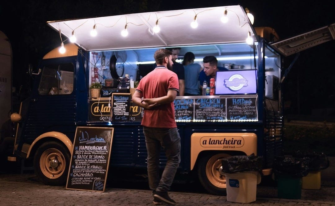 a person standing next to a food truck a person standing next to a food truck