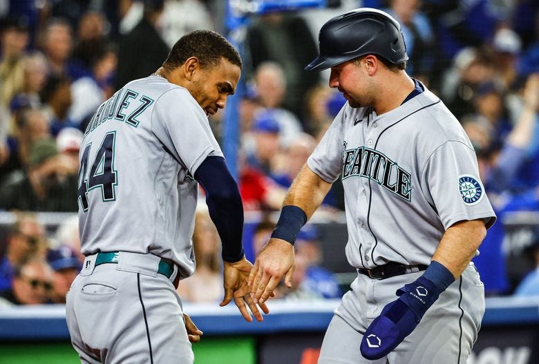 Julio Rodriguez congratulates Cal Raleigh as he scores on a double by Adam Frazier in the ninth inning to pull the Mariners ahead 10-9 as the Seattle Mariners play the Toronto Blue Jays in Game 2 of the American League Wild Card Game Saturday, Oct. 8, 2022 at Rogers Centre, in Toronto, Ontario, Canada. (Dean Rutz / The Seattle Times)