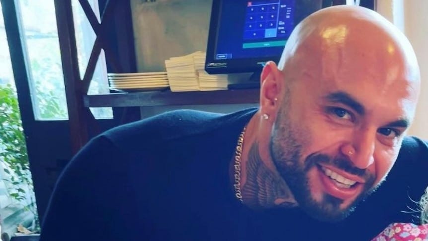 Photo of smiling man with black jumper and beard.