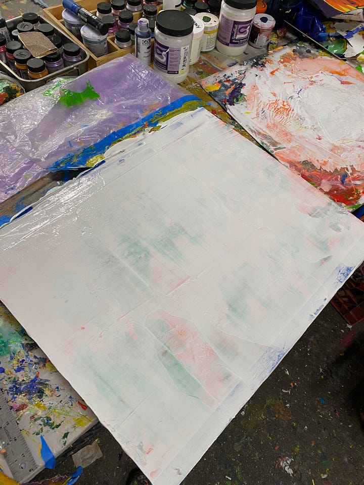 1st photo (left), painting panel on table covered in white paint with a section at the bottom covered in plastic. Second photo: painting with multiple layers of white leafy stencils over a silver acrylic paint background.