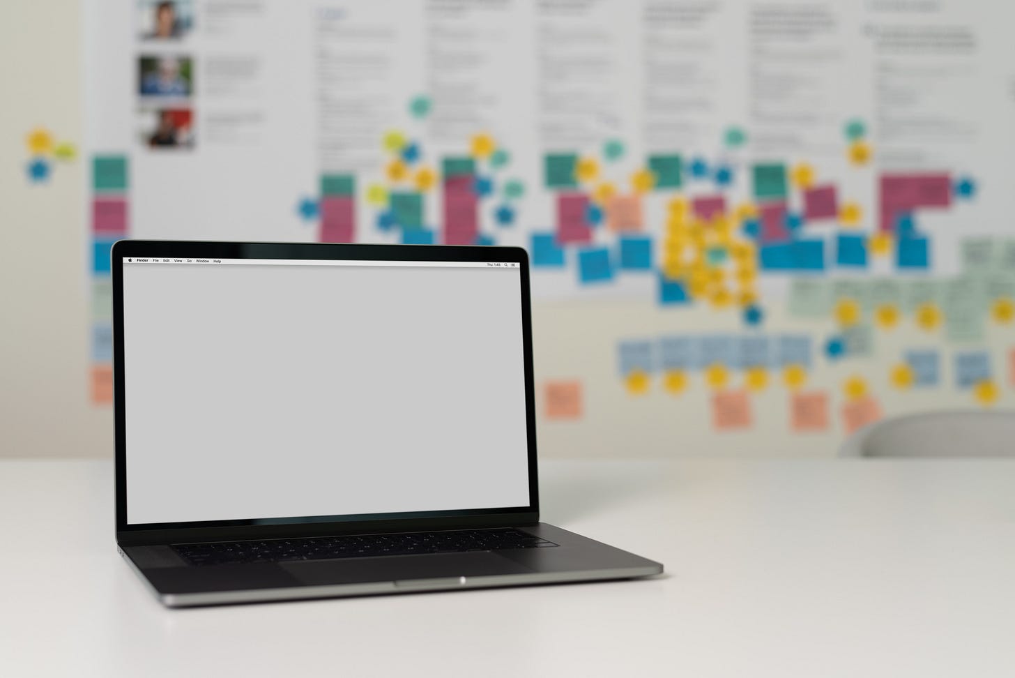 Un computer sul tavolo e una lavagna con tanti post-it sullo sfondo
