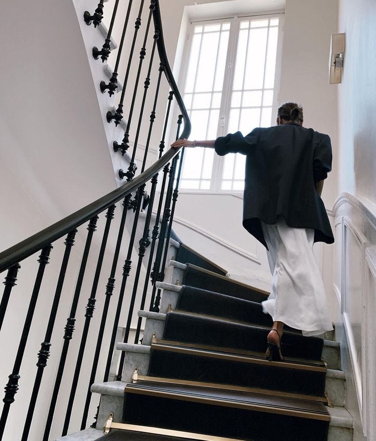This may contain: a woman is walking down the stairs with her coat on