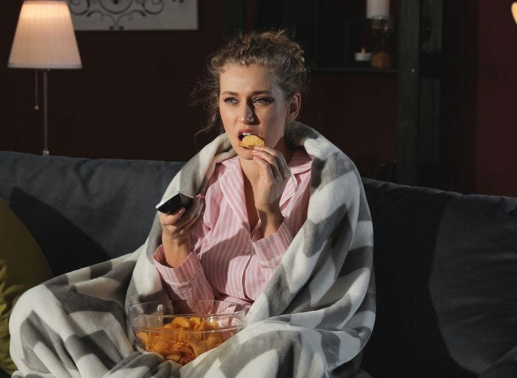 This may contain: a woman sitting on a couch eating food