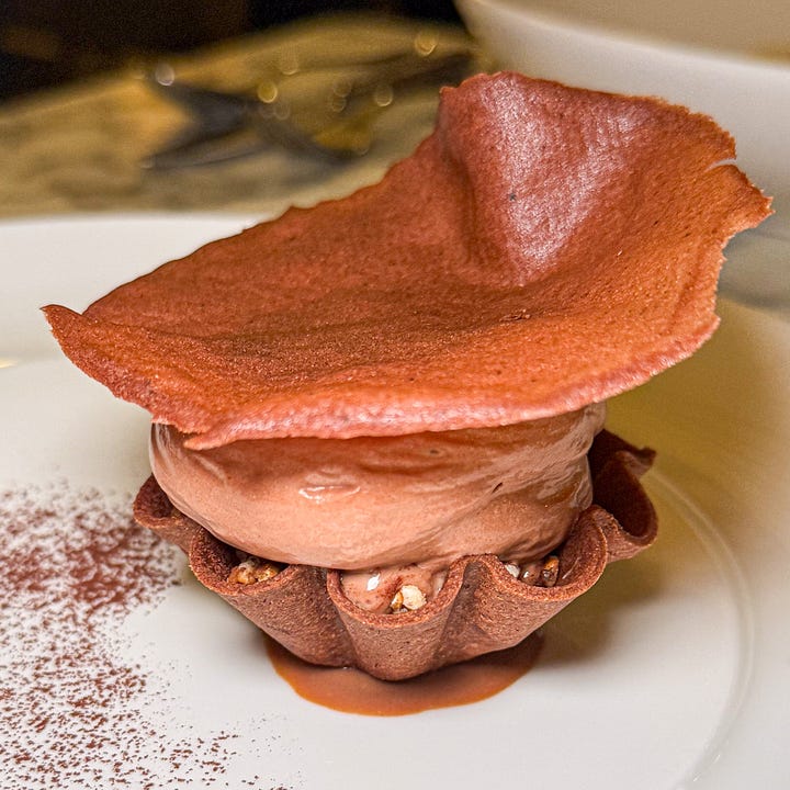 Citrus-and-fennel mousse ringed with orange and grapefruit segments and purple blossoms and Chocolate mousse in a chocolate tuile cup, capped with a thin chocolate wafer, in caramel