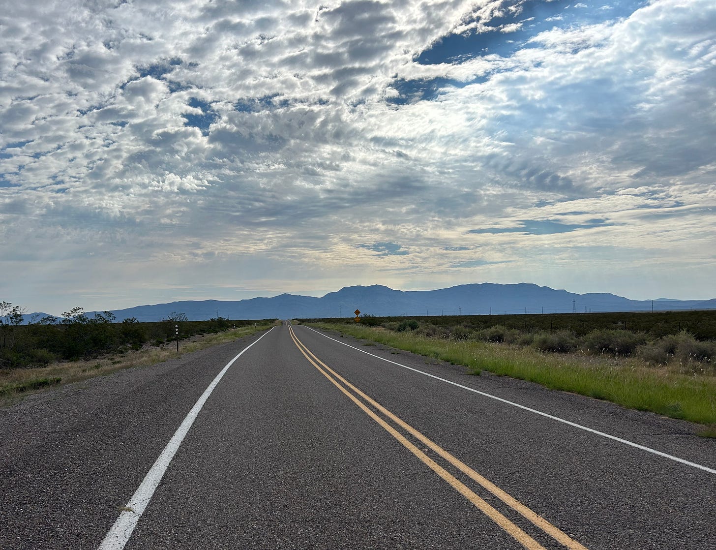 A long road leading into a dazzling New Mexico sky