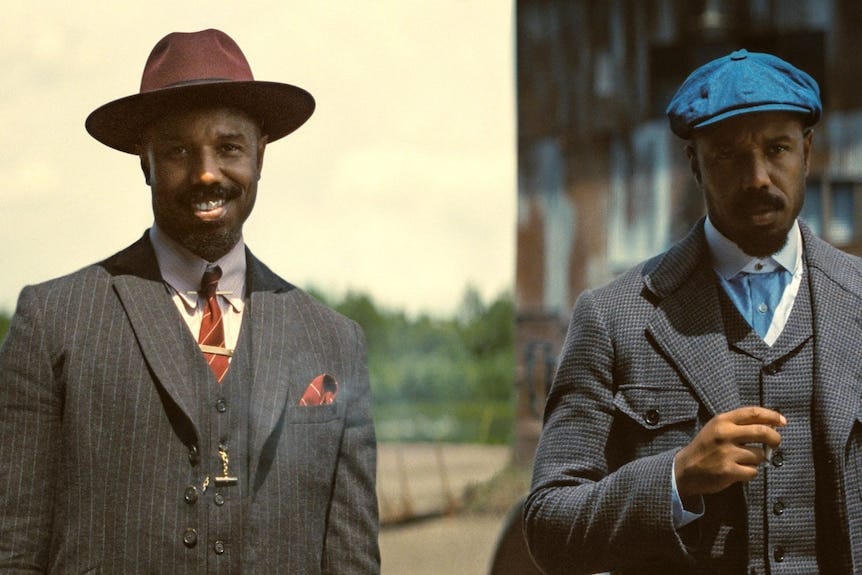 Two identical black men in 1930s' dress; one wearing a blue hat and tie, the other brown