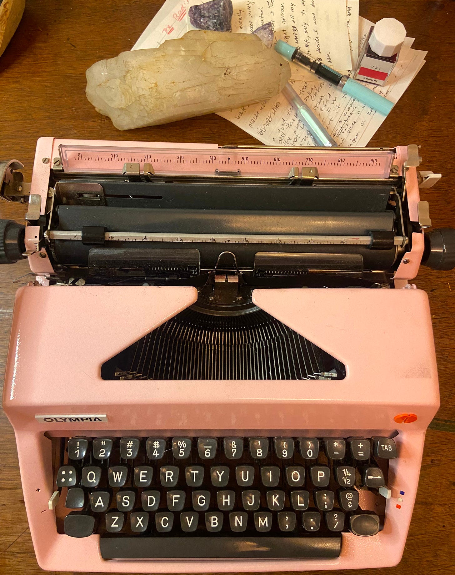 Overhead shot of pink typewriter, behind it, rocks and handwritten pages. Overhead shot of pink typewriter, behind it, rocks and handwritten pages.