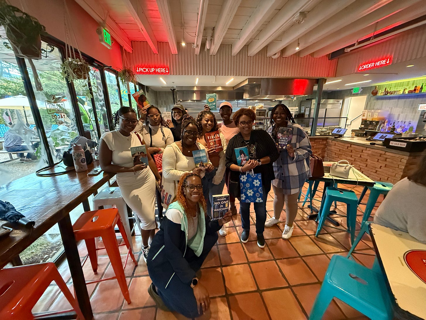 A group of Black women are holding books and posed for a photo at a restaurant. A group of Black women are holding books and posed for a photo at a restaurant.