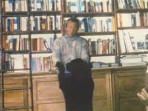 A man stands in a bookstore with a black dog jumping on him.