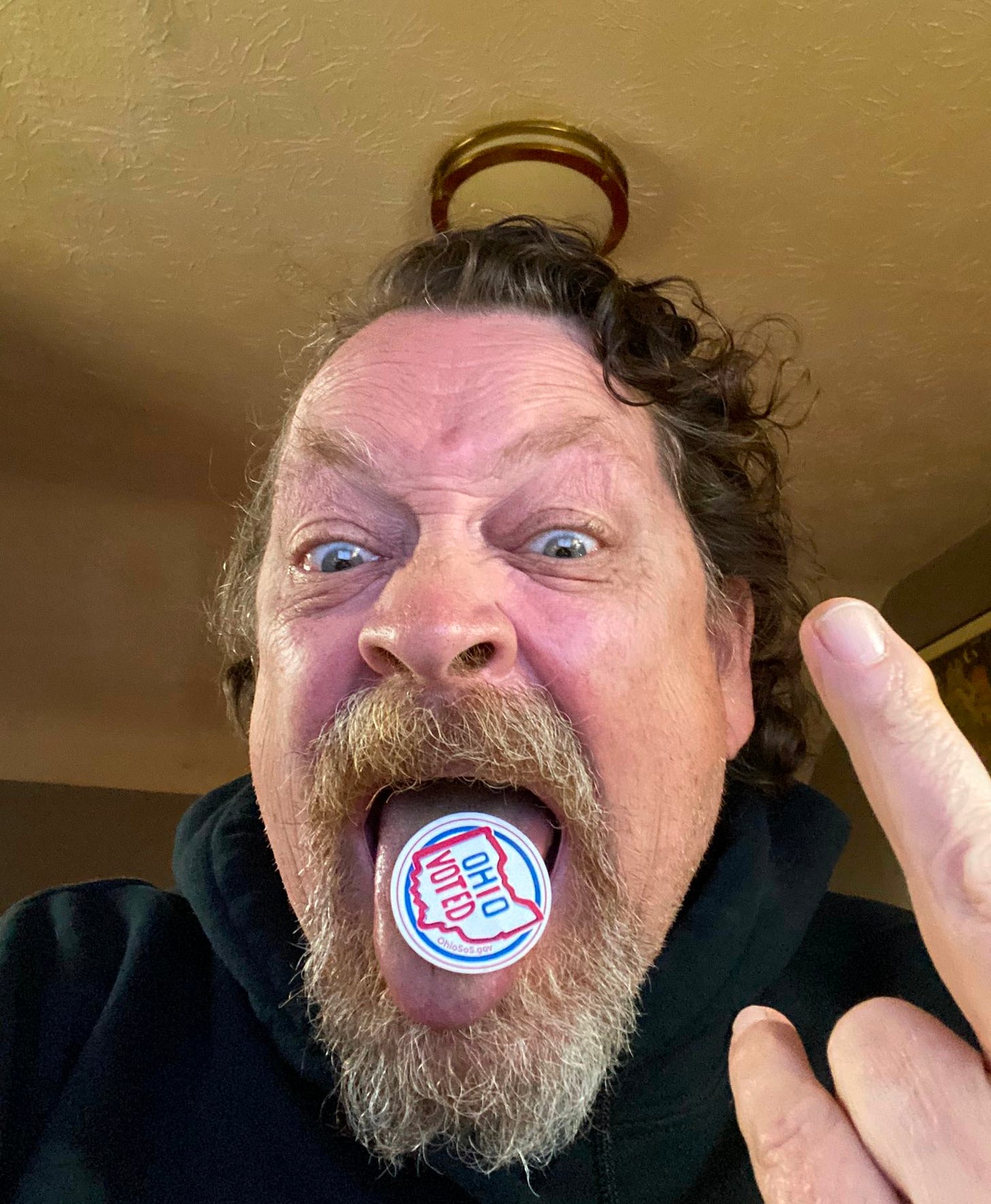Dan Chaon, crazed and bearded author, poses dramatically with an "I Voted" sticker on his tongue like a giant tab of acid Dan Chaon, crazed and bearded author, poses dramatically with an "I Voted" sticker on his tongue like a giant tab of acid