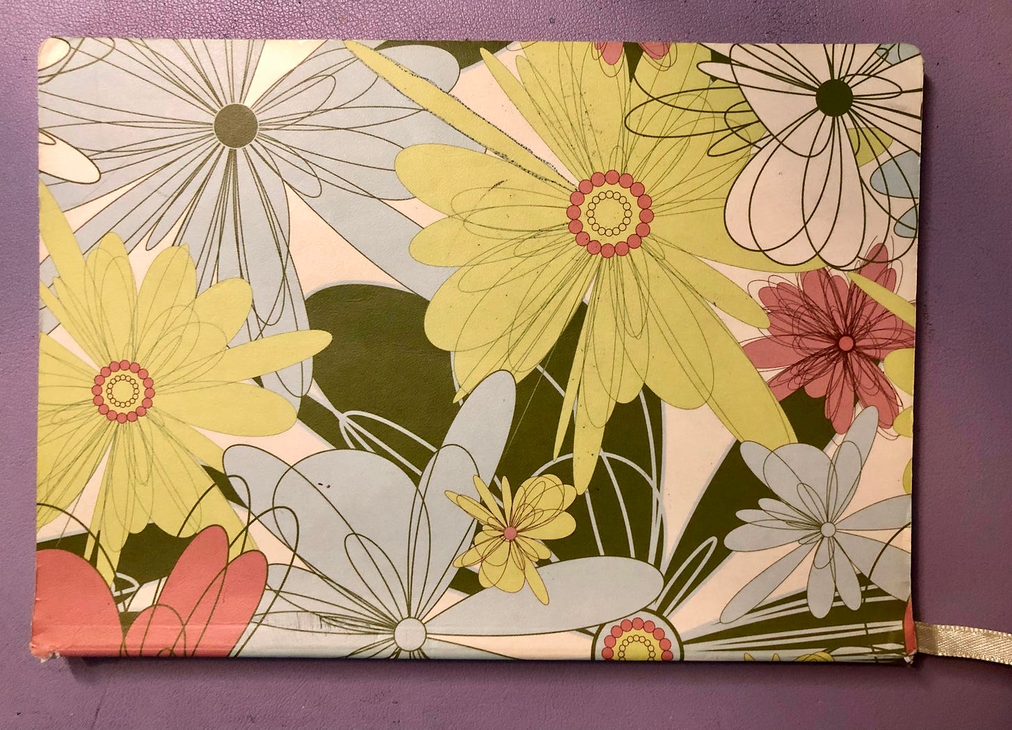 A green, pink, blue, and white floral patterned notebook.