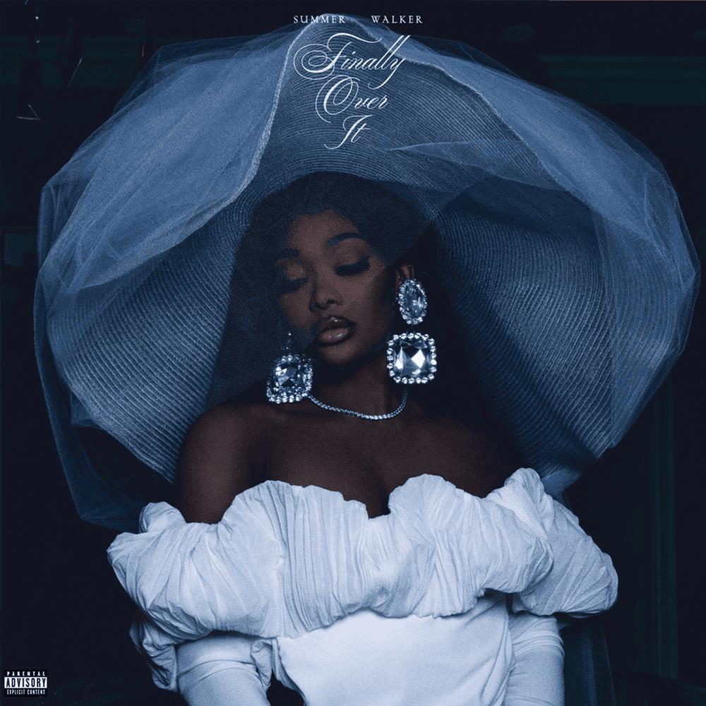 Summer Walker in bold diamond earrings and a necklace in a white dress and huge, dramatic light colored hat.