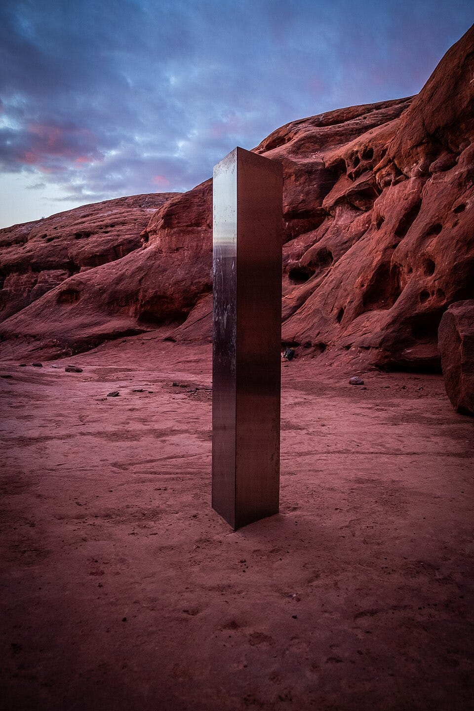 A monolith in the desert, depicting a shiny object in a remote and inhabited place.