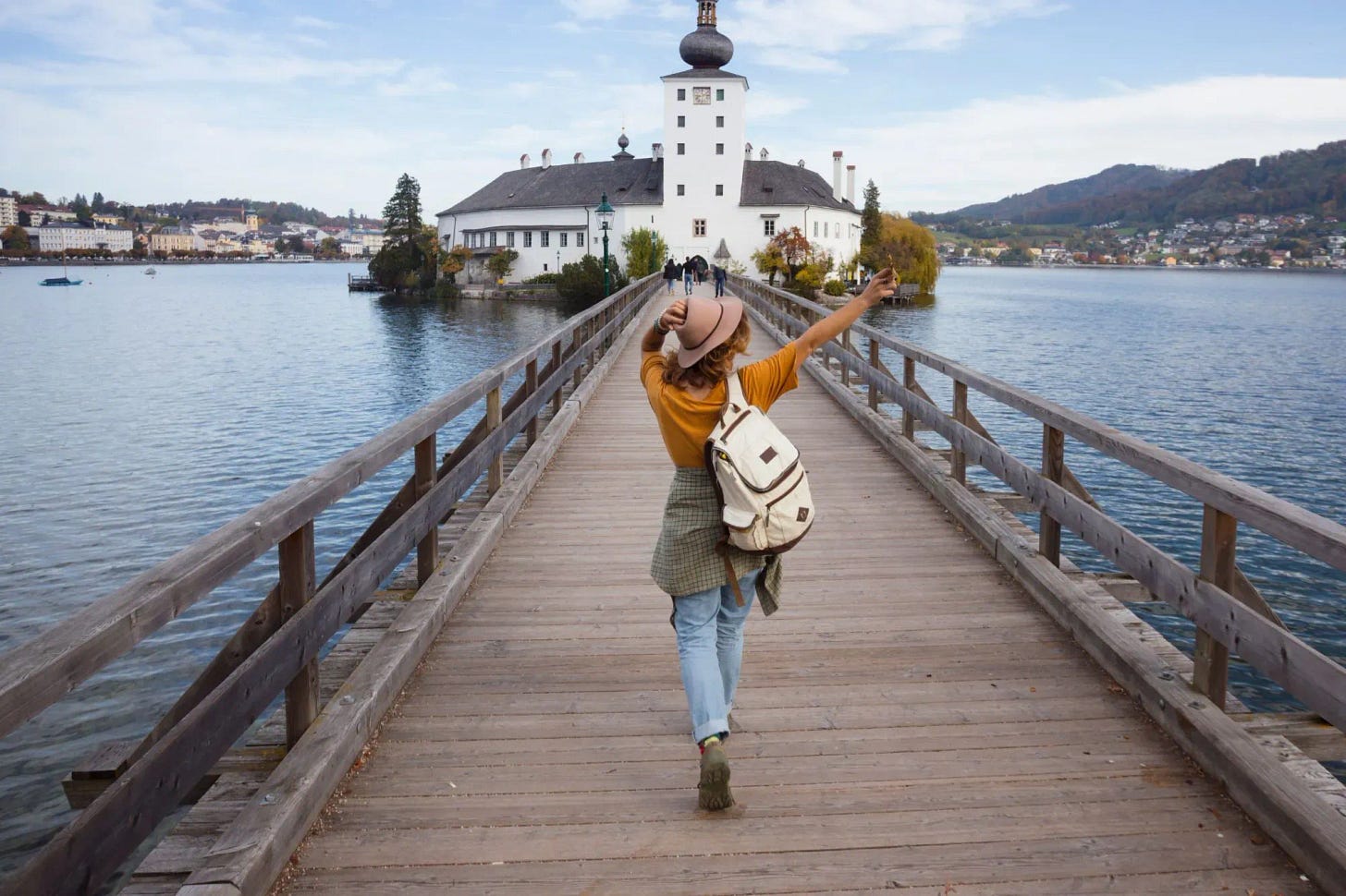 A happy woman bridging over to a lake castle on her vacation