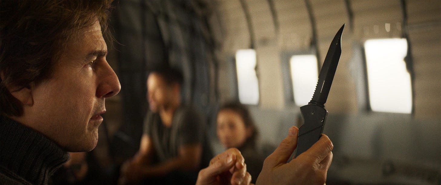 Tom Cruise as Ethan Hunt holding and looking at a small combat knife while in an airplane. Tom Cruise as Ethan Hunt holding and looking at a small combat knife while in an airplane.