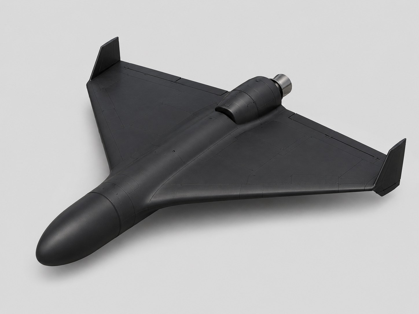 Three-quarter view of a black delta-wing drone showing a cylindrical jet engine pod mounted on the upper rear fuselage