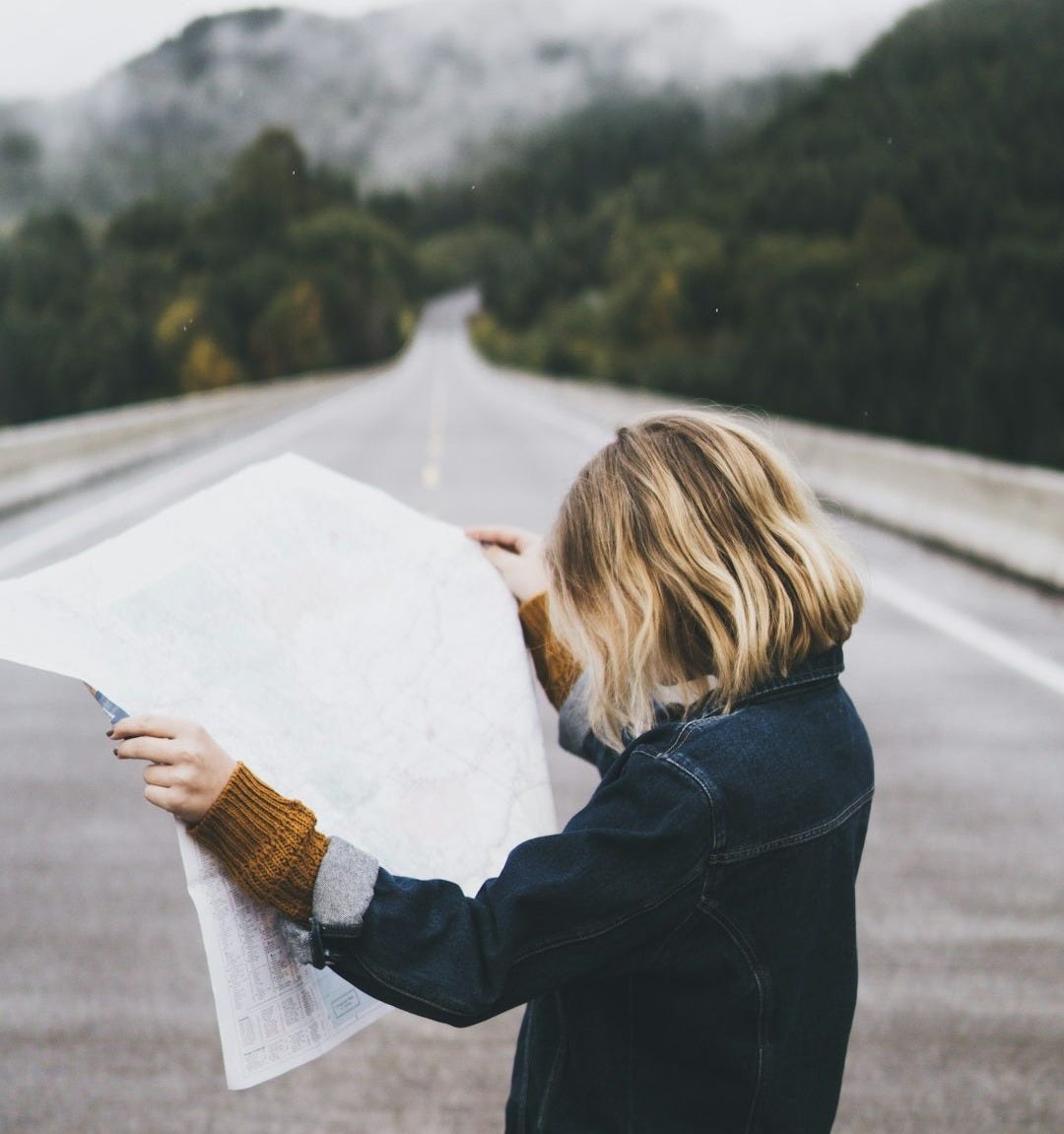 woman looking at map while standing on road