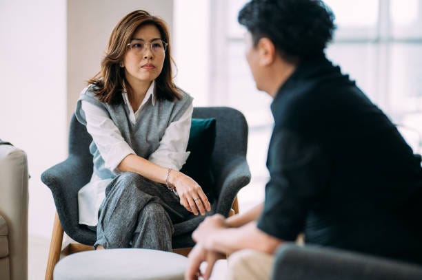 navigating challenges: a therapeutic dialogue between an asian female psychologist and a mature man - consulting patient at modern office - emotional conflict stock pictures, royalty-free photos & images