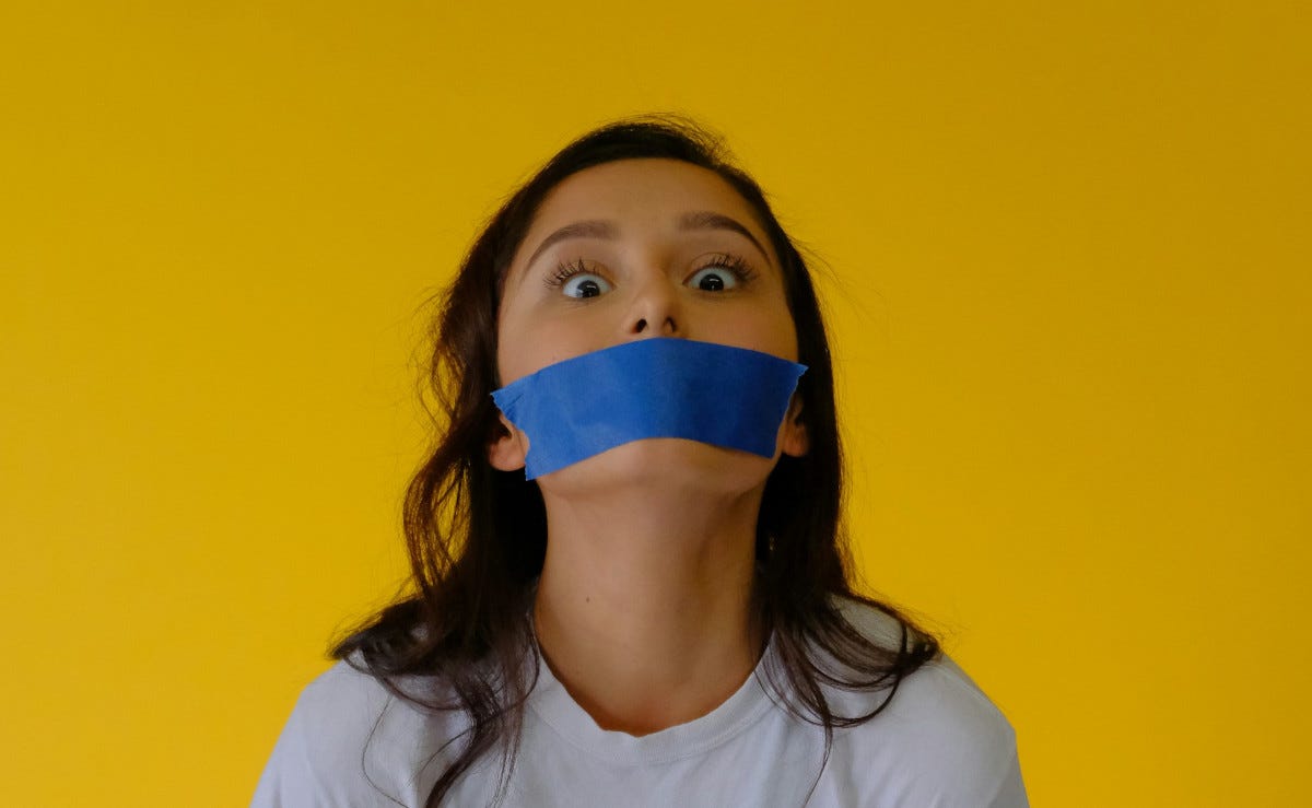 Woman with blue tape covering her mouth to silence her Woman with blue tape covering her mouth to silence her