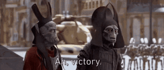 a couple of aliens are standing next to each other and one of them is talking about victory .