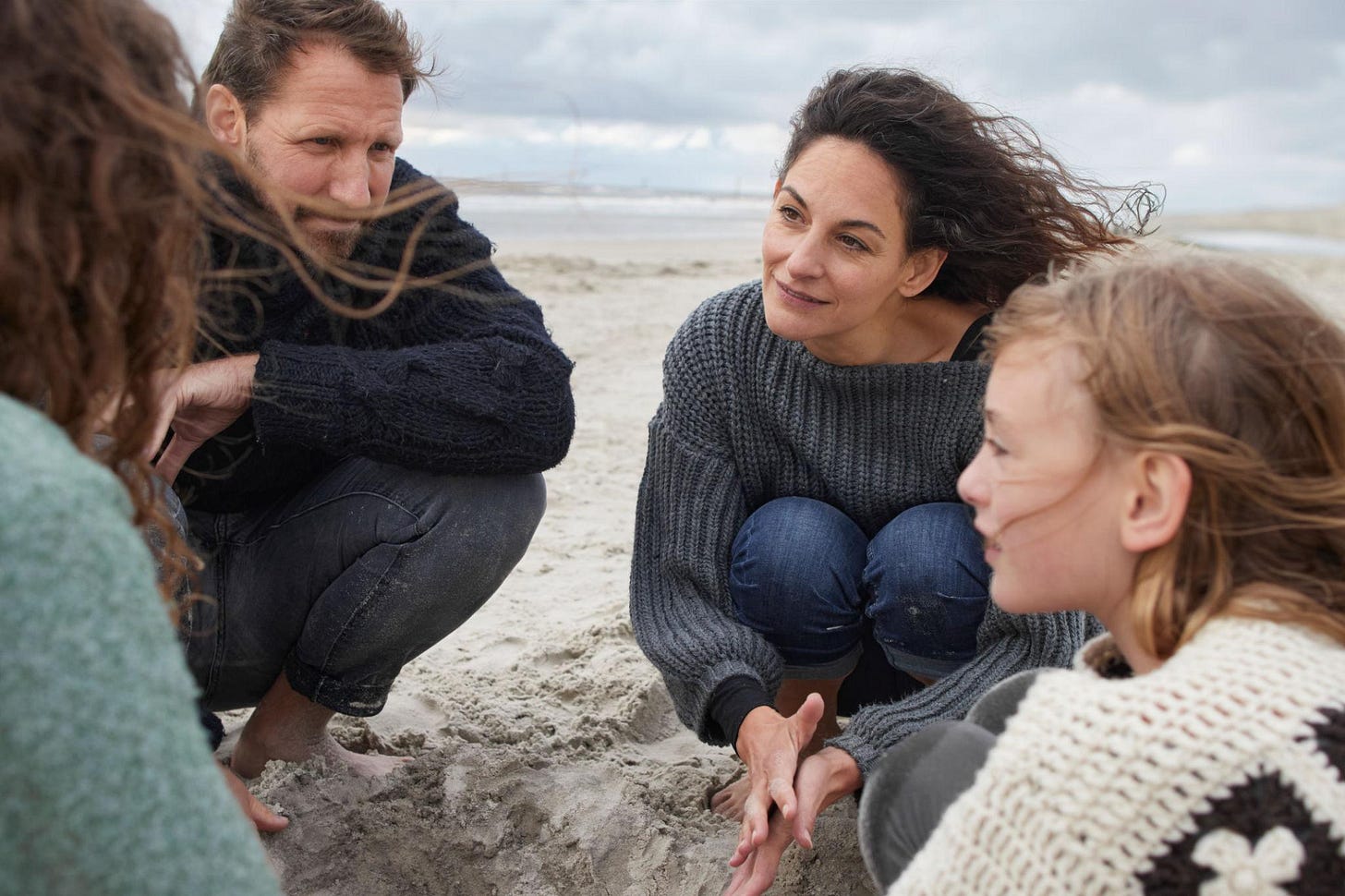 Family crouching on the beach