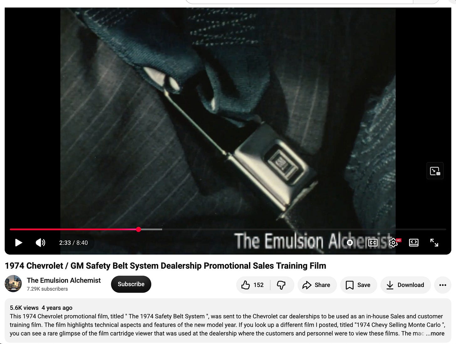 A still from a 1974 GM dealership training film showing a driver buckling a seat belt in a Chevrolet.