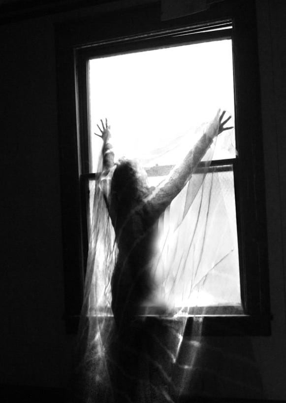 a woman standing in front of a window in a dark room
