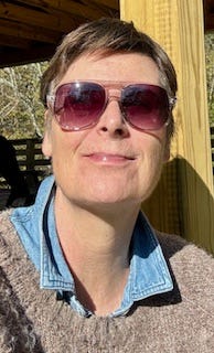 a woman sitting on a deck with sunglasses on