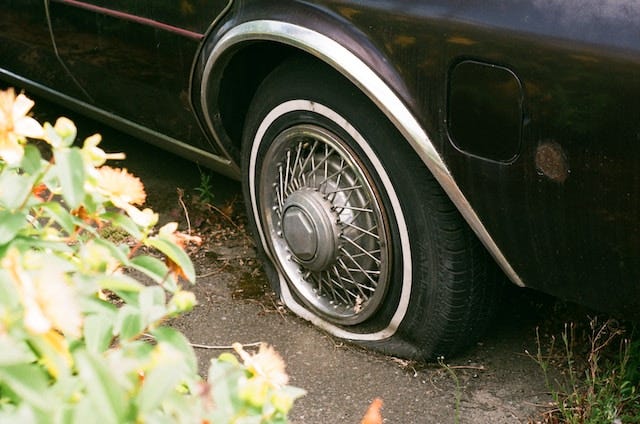 Photo of a car with a flat tyre. Photo of a car with a flat tyre.