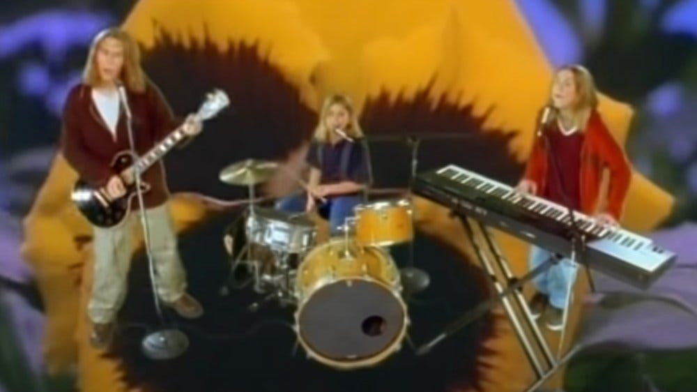 a still from the "Mmmbop" music video--the boys playing their instruments over the giant image of a flower.